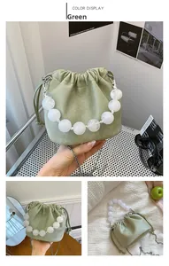 Détail du sac seau vert avec poignée en perles marbrées et bandoulière chaîne