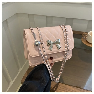 Detail of pink quilted crossbody bag with silver metal bow and chain shoulder strap