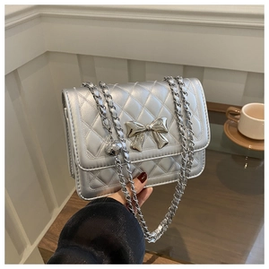 Close-up of a silver quilted leather bag with a metallic bow and chain shoulder strap