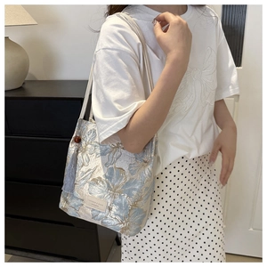 Detailed shot of floral jacquard tote bag with blue tassels and leather brand label