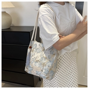 Detail of floral jacquard tote bag with purple tassel and leather shoulder strap