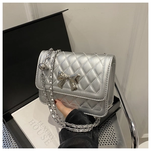 Detail of silver metallic quilted bag with a mirror-finish bow clasp and chain strap