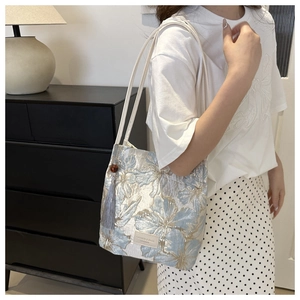 Detail of light blue floral jacquard tote bag with cream strap and blue tassel accent