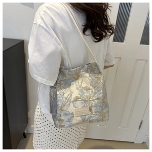 Detail of floral jacquard tote bag with leather tag and elegant tassel accessory