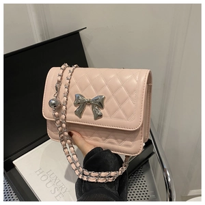 Detail of light pink quilted handbag with large silver bow and chain strap