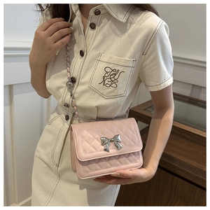 Detailed view of pink quilted handbag with silver metal bow and chain shoulder strap