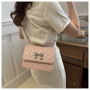 Detailed view of pink quilted shoulder bag with silver bow buckle on model
