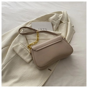 Detail of minimalist beige shoulder bag with gold chain strap on a white blazer