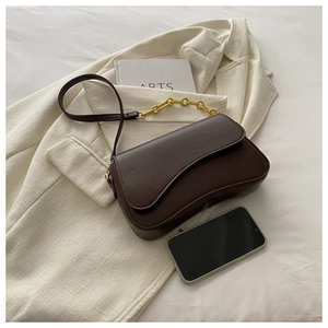 Detail of a dark brown vintage saddle bag featuring a unique wavy flap and gold chain strap