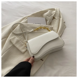 French style white curved shoulder bag with gold chain over a beige textured blazer