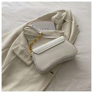 White faux leather baguette bag on blazer with gold chain strap detail view