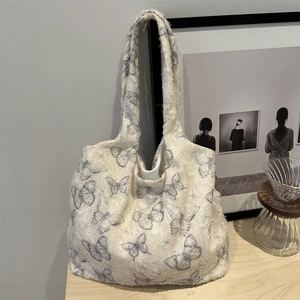 Off-white canvas tote bag with butterfly print and frayed edges on a wooden table