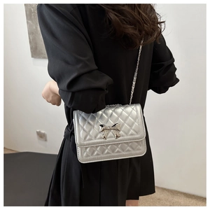Detailed close-up of a silver quilted chain bag with a metal bow accent and diamond texture