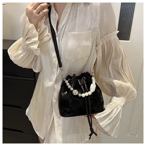 Détail d'un sac seau noir avec poignée en perles et billes argentées et cordon de serrage