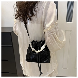 Detail of black velvet bucket bag featuring decorative pearl and crystal bead handle