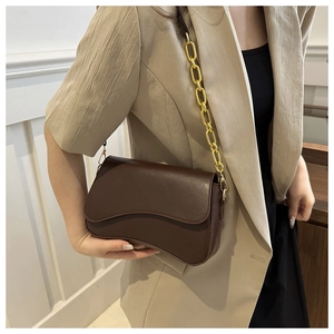 Detail of dark brown leather handbag with wave-cut flap and golden chain strap