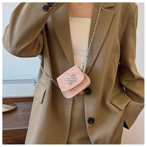 Gros plan du mini sac rose avec boucle papillon argentée sur un costume marron