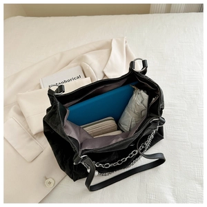 Detail view of large tote bag capacity holding a folder, wallet, umbrella and chain decor