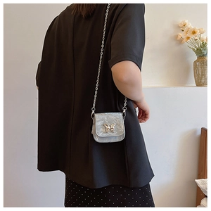 Mini sac argenté chic avec fermoir papillon en métal porté par un mannequin en extérieur