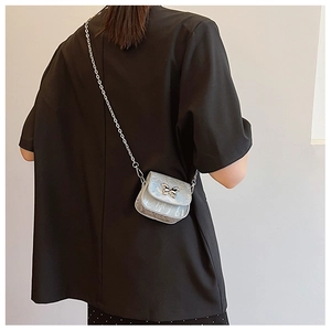 Détail du sac à chaîne argenté avec ornement papillon en métal et texture marbrée