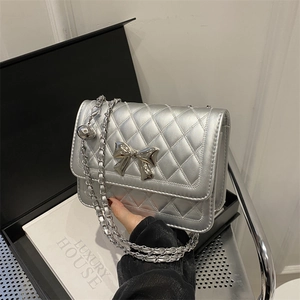 Detail view of silver quilted chain bag with metallic bow and adjustable metal ball buckle