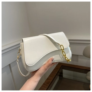 Detail of white saddle bag featuring gold chain strap and elegant leather texture