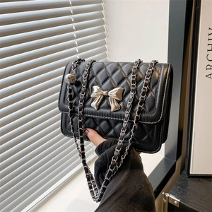 Fashionable black quilted chain bag with silver bow accent and leather woven strap