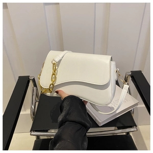Close-up of white leather shoulder bag with wavy flap and chunky gold chain strap