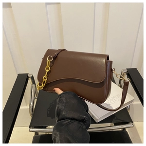 Detailed view of deep brown leather crossbody bag with chic gold chain and curved flap