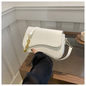 Detail of white leather shoulder bag featuring a bold gold chain and adjustable strap