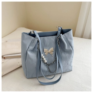 Detail of light blue tote bag with metallic butterfly and pearl chain on soft leather
