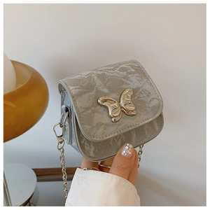 Détail du mini sac argenté avec boucle papillon en métal et bandoulière en chaîne