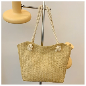 Detailed macro view of woven straw tote bag texture with white cotton rope handle knots