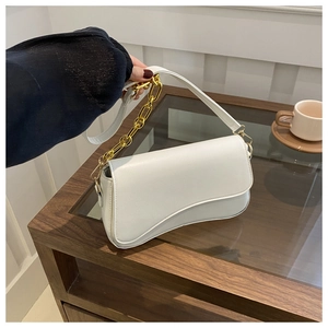 Detailed shot of a white baguette bag with a wavy flap and thick gold chain link