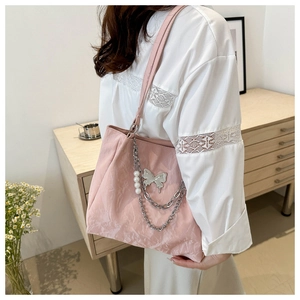 Detail of pink tote bag with silver butterfly charm, pearls, and metal chain decoration