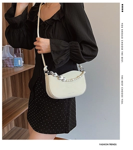 Detail of hobo bag featuring pearl chain, silver heart pendant and FASHION & BAGS logo