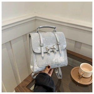 Close-up of a silver-grey mini backpack with metallic butterfly and glitter texture