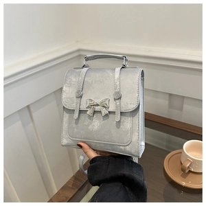 Détail du sac gris argenté avec nœud métallique et poignée supérieure structurée