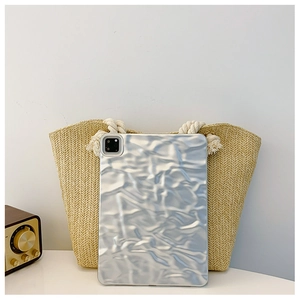 Close-up of silver crinkle foil texture tablet case placed against a straw woven tote bag