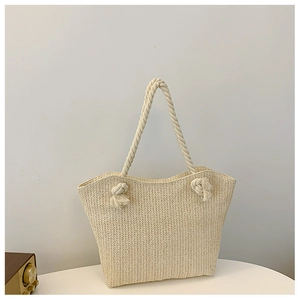 Detail of herringbone weave texture and thick knotted rope handle on cream straw tote bag