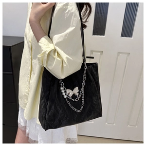 Detail of black tote bag with silver chain, butterfly charm and pearl accents on fabric