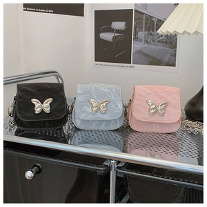 Trois mini sacs bandoulière plissés avec boucle papillon argentée sur un chariot métal