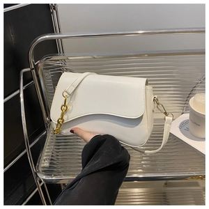 Close-up of elegant white shoulder bag with chunky gold chain detail and leather strap