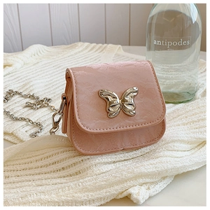 Gros plan d'un mini sac rose avec fermoir papillon doré sur un fond en tricot doux