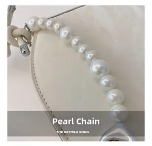 Detailed close-up of a white leather bag with decorative white pearls and silver hardware