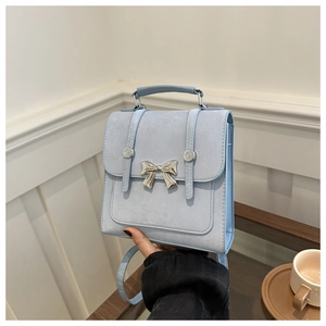 Détail d'un sac à main bleu clair avec boucle nœud argentée et rivets décoratifs