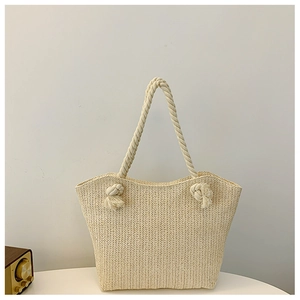Detail of herringbone weave texture and knotted rope handle on the straw tote bag