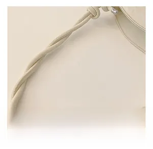 Close-up of beige leather shoulder bag featuring a unique spiral woven strap detail