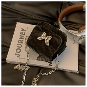 Détail du mini sac bandoulière noir avec boucle papillon argentée et chaîne chic