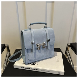 Détail du sac à main bleu clair en cuir givré avec nœud métallique argenté élégant